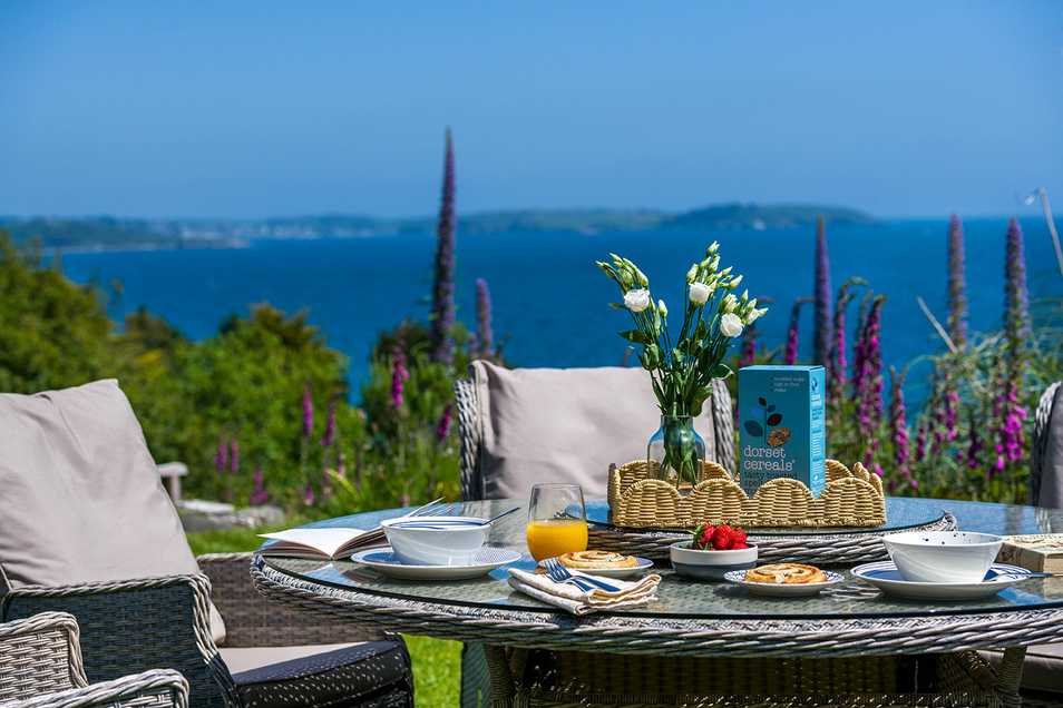 breakfast table laid in the garden at Dreemskerry, showcasing the sea views